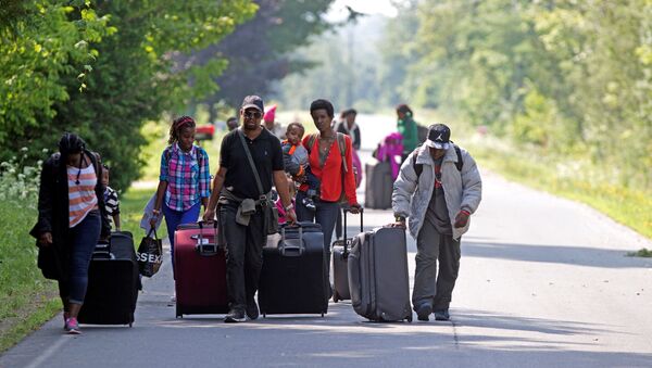 Three families that claimed to be from Burundi walk down Roxham Road to cross into Quebec at the US-Canada border in Champlain, New York,  August 3, 2017 - Sputnik International