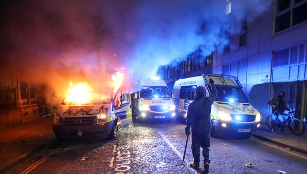 A demonstrator gestures near a burning police vehicle during a protest against a new proposed policing bill, in Bristol, Britain, 21 March 2021. - Sputnik International