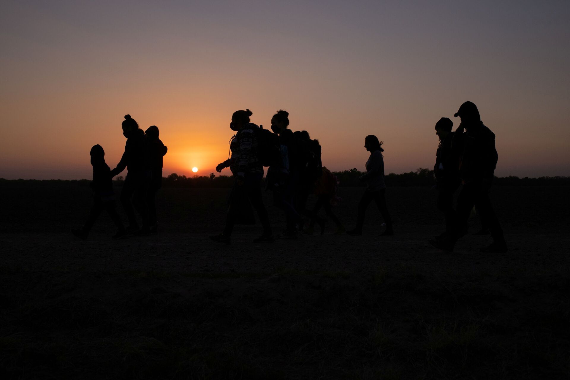 The sun rises as asylum-seeking migrants' families from Honduras and El Salvador walk towards the border wall after crossing the Rio Grande river into the United States from Mexico on a raft, in Penitas, Texas, U.S., March 26, 2021 - Sputnik International, 1920, 07.09.2021