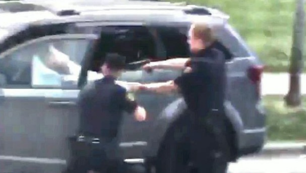 A still from cell phone footage included in the federal complaint against Kenosha Police Officer Rusten Sheskey by Jacob Blake, a 29-year-old Black man who Sheskey shot six times in the back during an August 23, 2020 encounter. In the image, Sheskey is holding onto the back of Blake's shirt as he fires into Blake's back. - Sputnik International