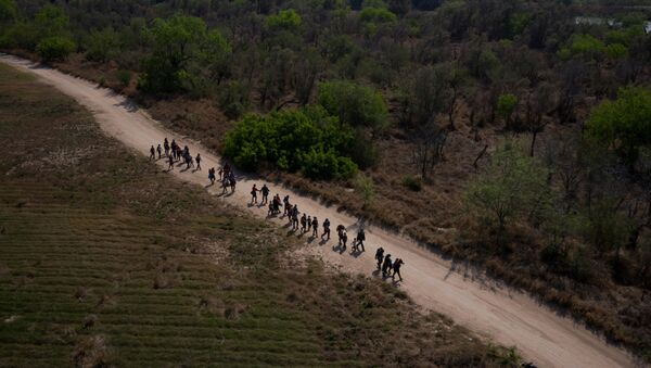 Asylum seeking migrant families from Central America walk towards the border wall after crossing the Rio Grande river into the United States from Mexico on rafts in Penitas, Texas, U.S., March 26, 2021 - Sputnik International