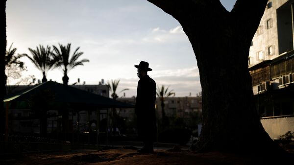 An ultra-Orthodox Jewish man looks on as others dip cooking utensils in boiling water to remove remains of leaven in preparation for the upcoming Jewish holiday of Passover as the country begins to emerge from coronavirus disease (COVID-19) pandemic closures due to it's rapid vaccine roll-out, in Ashdod, Israel March 25, 2021.  - Sputnik International