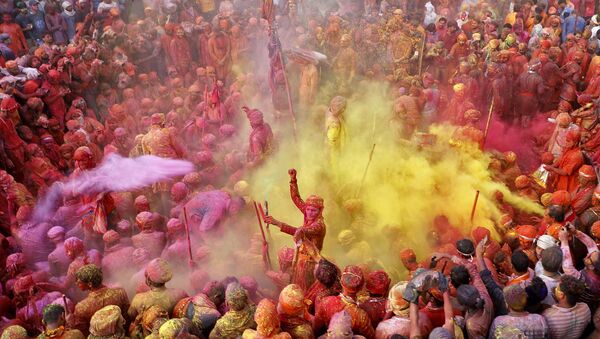 Men daubed in colours throw coloured powder at each other during Lathmar Holi celebrations, amidst the spread of the coronavirus disease (COVID-19), in the town of Nandgaon, in the northern state of Uttar Pradesh, India, March 24, 2021.  - Sputnik International