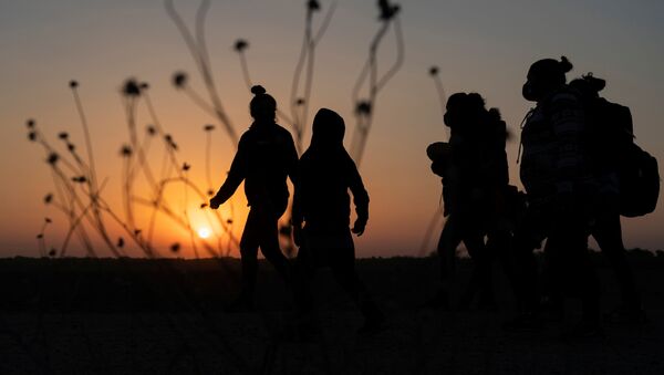 Asylum-seeking migrants' families walk towards the border wall after crossing the Rio Grande river into the United States from Mexico, in Penitas, Texas, U.S., March 26, 2021. - Sputnik International