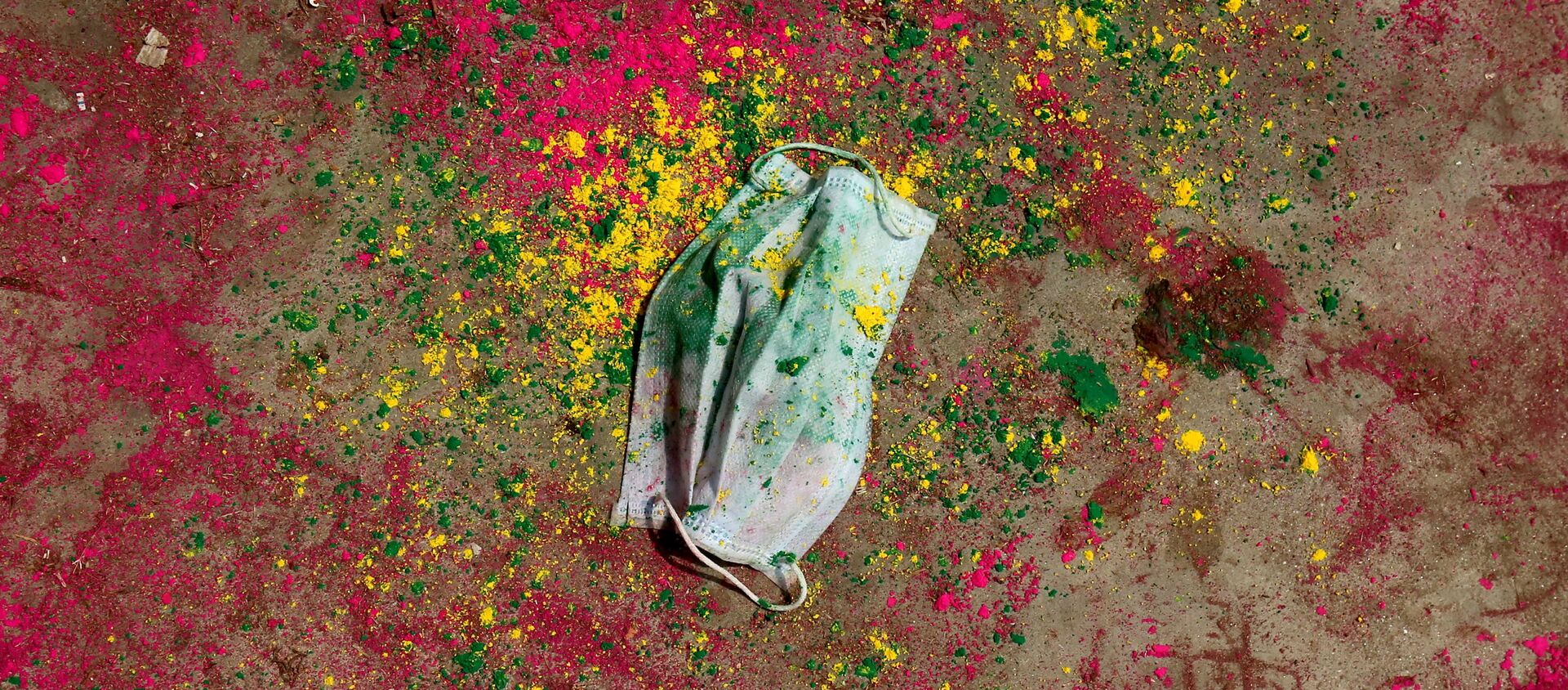 A face mask lies on a road covered with colour powder during Holi celebrations, amidst the spread of the coronavirus disease (COVID-19), in Chennai, India, March 29, 2021. - Sputnik International, 1920, 07.04.2021