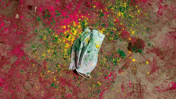 A face mask lies on a road covered with colour powder during Holi celebrations, amidst the spread of the coronavirus disease (COVID-19), in Chennai, India, March 29, 2021. - Sputnik International