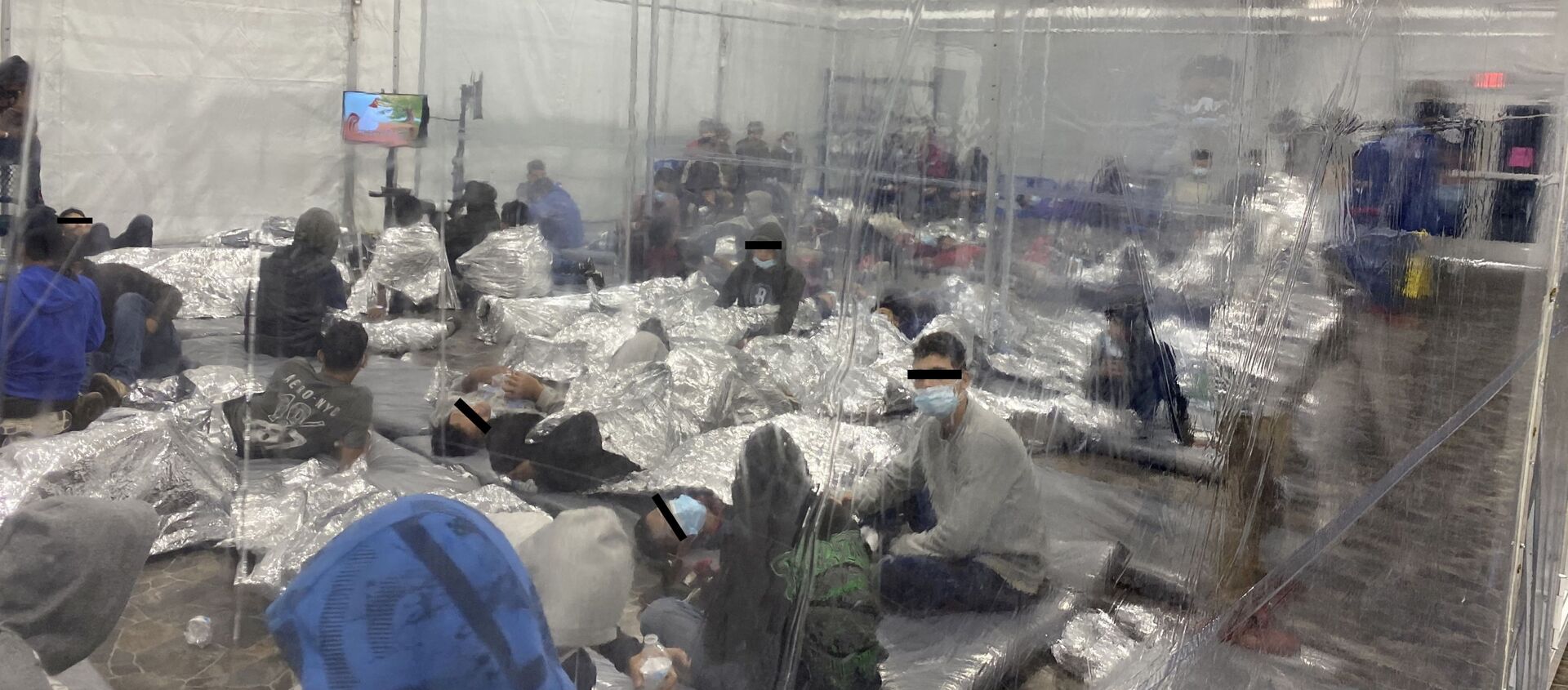 Migrants crowd a room with walls of plastic sheeting at the U.S. Customs and Border Protection temporary processing center in Donna, Texas, U.S. in a recent photograph released March 22, 2021 - Sputnik International, 1920, 29.03.2021