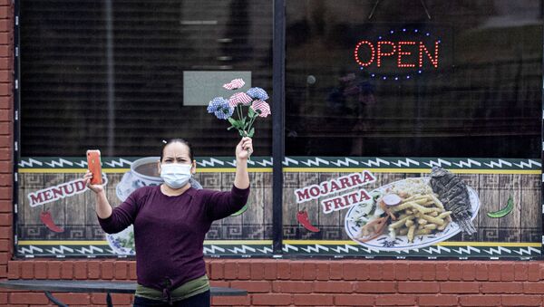 A woman holds plastic flowers as the motorcade of U.S. President Joe Biden drives past following a visits to the Centers for Disease Control and Prevention (CDC) in Atlanta, Georgia, U.S., March 19, 2021.  - Sputnik International