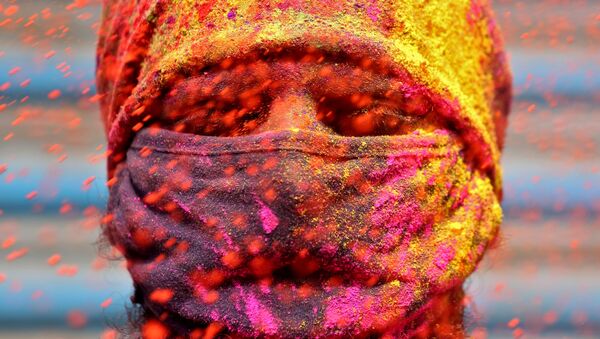 A man wearing a protective face mask reacts as colour powder is thrown towards him during Holi celebrations, amidst the spread of the coronavirus disease (COVID-19), in Chennai, India, March 29, 2021. - Sputnik International