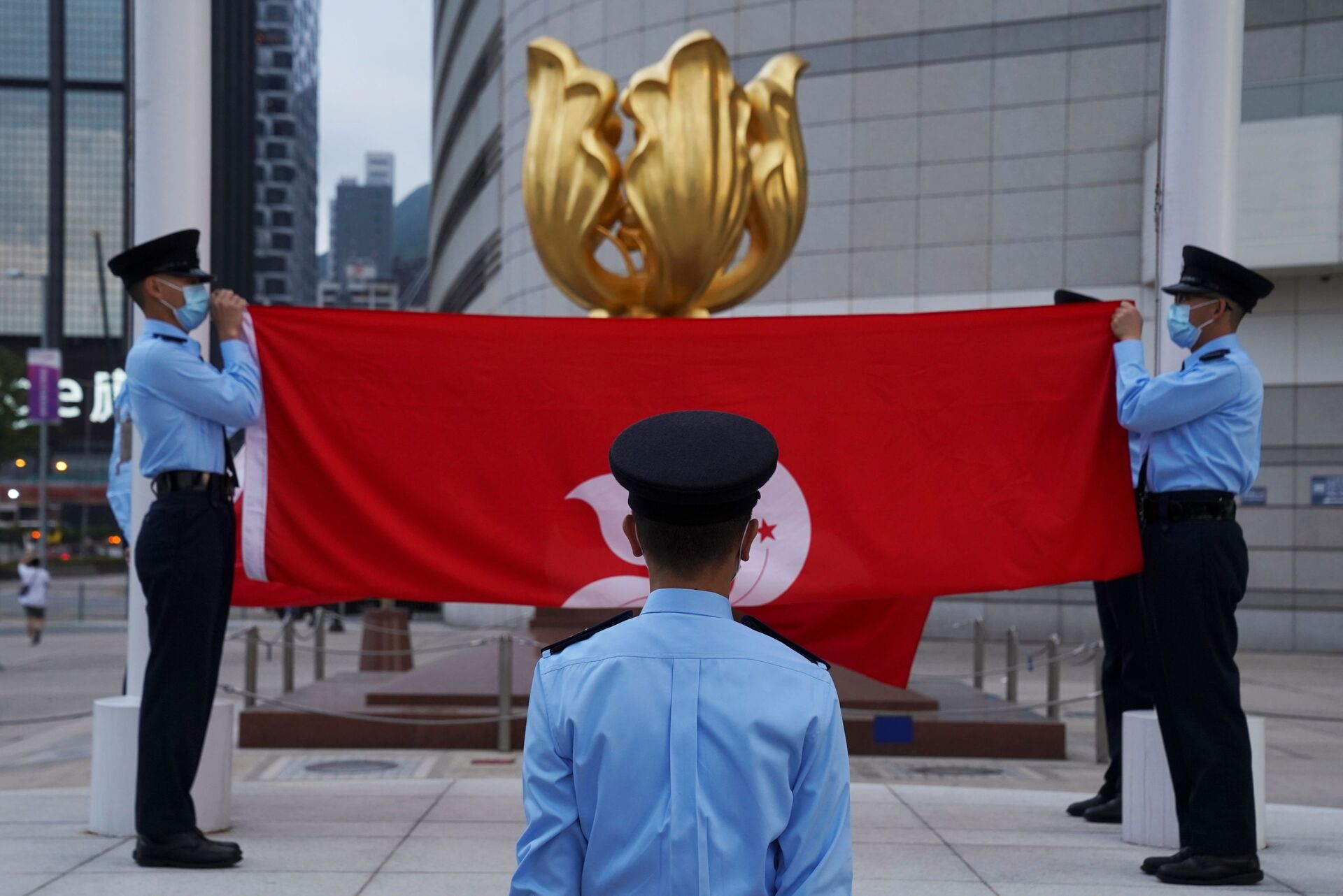 Police officers fold Chinese and Hong Kong flags at a flag-lowering ceremony in front of the Golden Bauhinia statue on the square, in Hong Kong, China March 30, 2021.  - Sputnik International, 1920, 15.11.2021