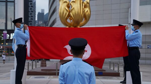 Police officers fold Chinese and Hong Kong flags at a flag-lowering ceremony in front of the Golden Bauhinia statue on the square, in Hong Kong, China, 30 March 2021.  - Sputnik International