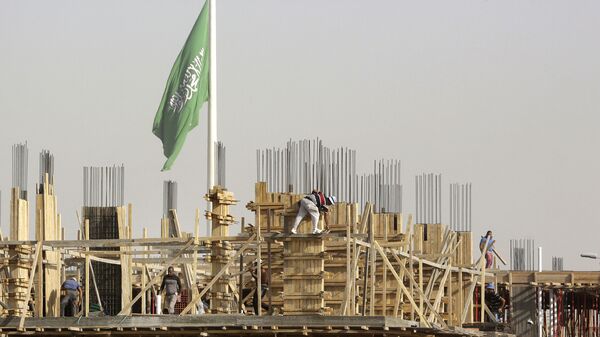 Egyptian workers assemble concrete forms at a building site as a giant Saudi flag hangs in the background at King Abdullah Square in Jiddah, Saudi Arabia, Sunday, March 14, 2021 - Sputnik International