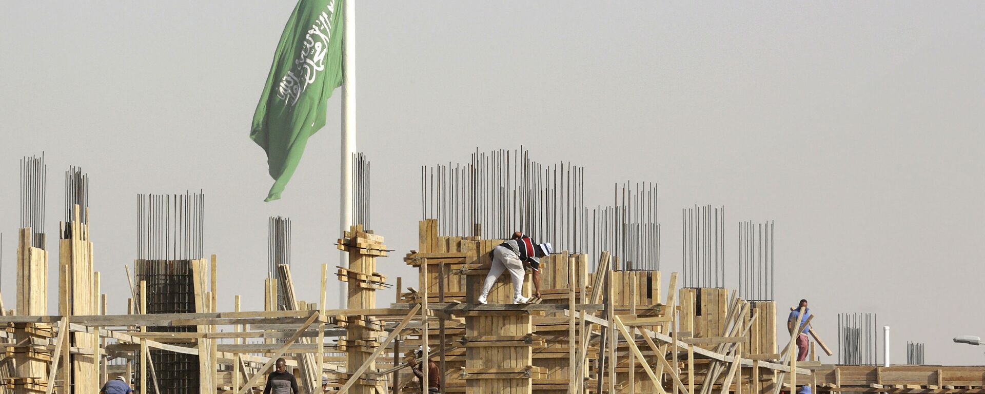 Egyptian workers assemble concrete forms at a building site as a giant Saudi flag hangs in the background at King Abdullah Square in Jiddah, Saudi Arabia, Sunday, March 14, 2021 - Sputnik International, 1920, 12.03.2022