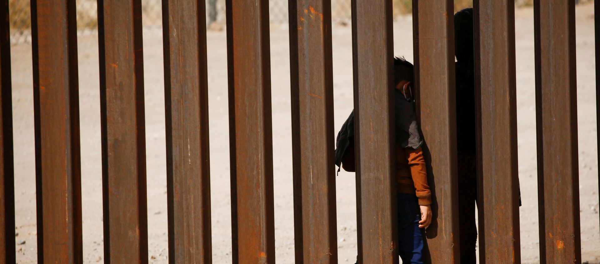 Migrant child is seen through the border wall after crossing the Rio Bravo river to turn himself with his family in to U.S. Border Patrol agents to request for asylum in El Paso, Texas, U.S., as seen from Ciudad Juarez, Mexico March 29, 2021 - Sputnik International, 1920, 01.04.2021