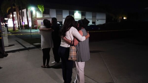 Unidentified people comfort each other as they stand near a business building where a shooting occurred in Orange, Calif., Wednesday, March 31, 2021 - Sputnik International