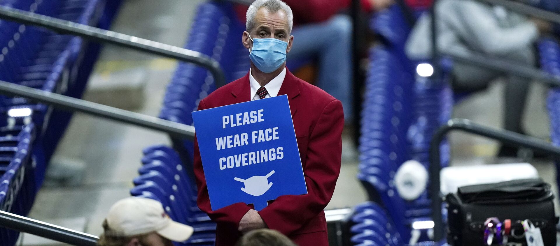 In this March 21, 2021, file photo, an usher holds a sign reminding fans to wear masks during a college basketball game between Houston and Rutgers in the second round of the NCAA tournament at Lucas Oil Stadium in Indianapolis - Sputnik International, 1920, 02.04.2021