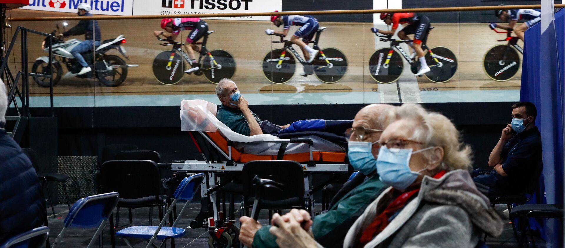 France's national cycling team trains as people wait to get a dose of the Comirnaty Pfizer-BioNTech COVID-19 vaccine as part of the coronavirus disease vaccination campaign at the indoor Velodrome National of Saint-Quentin-en-Yvelines in Montigny-le-Bretonneux, southwest of Paris, France, March 26, 2021 - Sputnik International, 1920