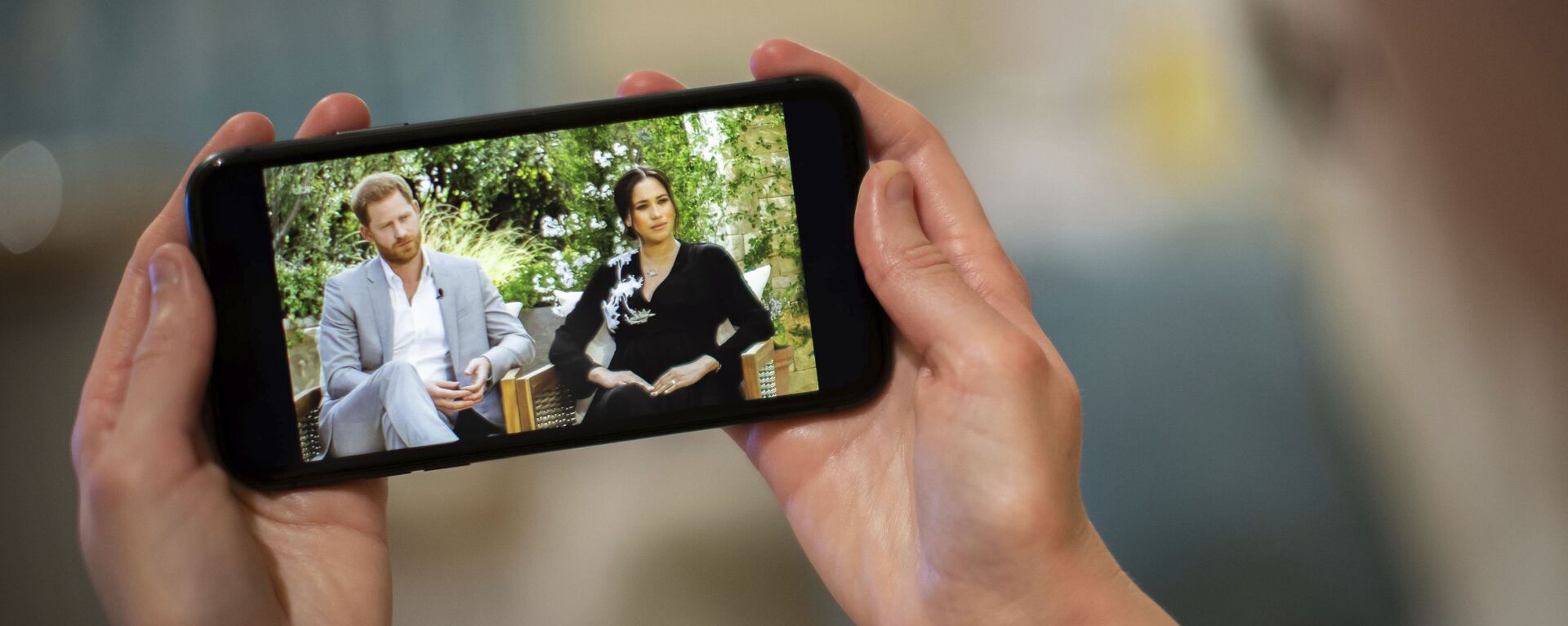 A man watches a phone screen showing an interview of Prince Harry and Meghan, The Duchess of Sussex, by Oprah Winfrey, in London Monday, March 8, 2021. - Sputnik International, 1920, 03.04.2021