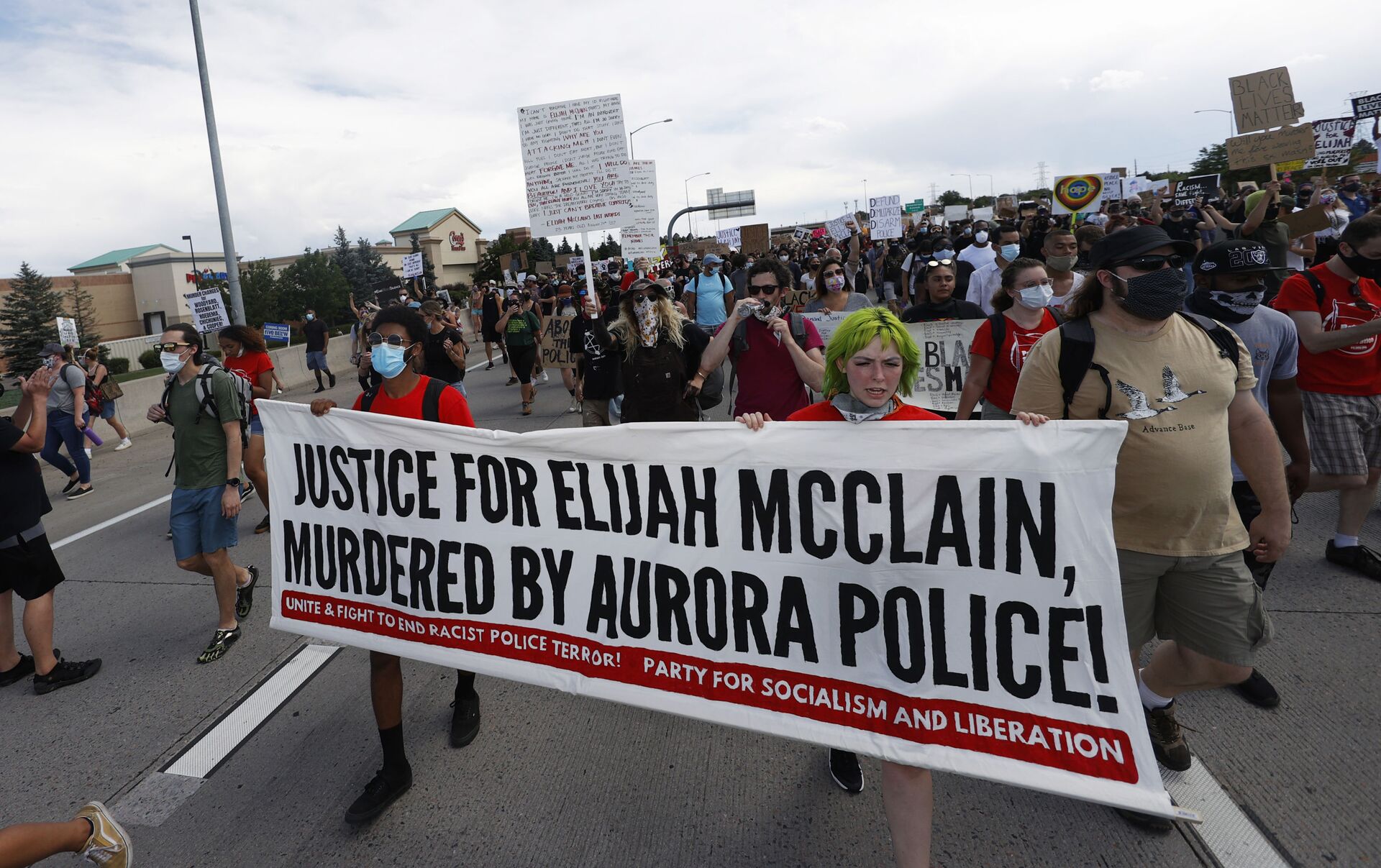 Demonstrators carry a banner while marching down Interstate 225 during a rally and march over the death of 23-year-old Elijah McClain, Saturday, June 27, 2020, in Aurora, Colo. McClain died in late August 2019 after he was stopped while walking to his apartment by three Aurora Police Department officers. - Sputnik International, 1920, 23.09.2022