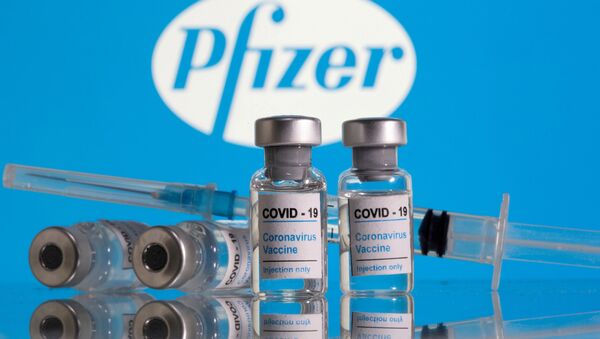 Vials labelled COVID-19 Coronavirus Vaccine and a syringe are seen in front of the Pfizer logo in this 9 February 2021 illustration - Sputnik International