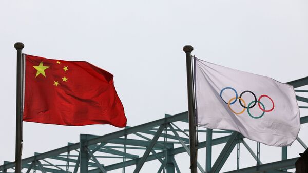 A Chinese national flag flutters next to an Olympic flag at the Beijing Organising Committee for the 2022 Olympic and Paralympic Winter Games, in Beijing, China March 30, 2021 - Sputnik International