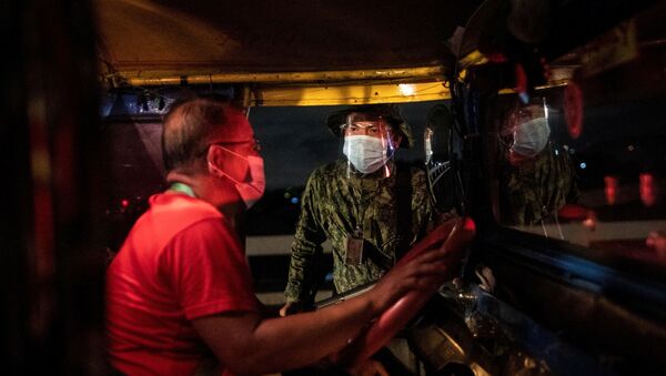 An armed policeman talks to a jeepney driver at a checkpoint placed to implement a curfew in the country's capital amid rising coronavirus disease (COVID-19) infections, in Quezon City, Metro Manila, Philippines, March 15, 2021. - Sputnik International