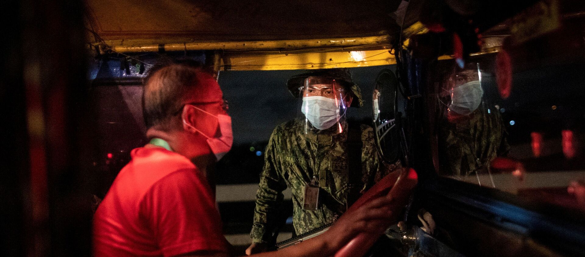 An armed policeman talks to a jeepney driver at a checkpoint placed to implement a curfew in the country's capital amid rising coronavirus disease (COVID-19) infections, in Quezon City, Metro Manila, Philippines, March 15, 2021. - Sputnik International, 1920, 07.04.2021