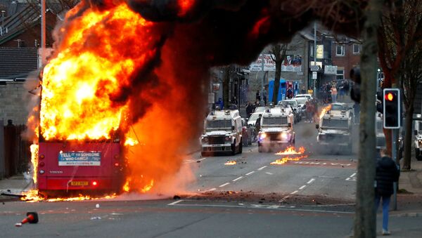 Police vehicles are seen behind a hijacked bus burns on the Shankill Road as protests continue in Belfast, Northern Ireland, 7 April 2021 - Sputnik International