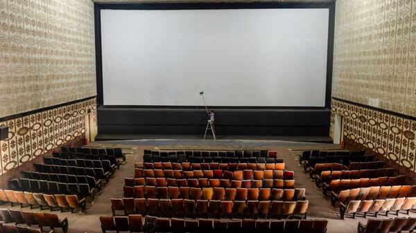 A worker cleans the screen of a cinema hall as part of preparations for a possible reopening after the government eased the lockdown restrictions previously imposed due to the Covid-19 coronavirus, in Chennai on October 8, 2020 - Sputnik International