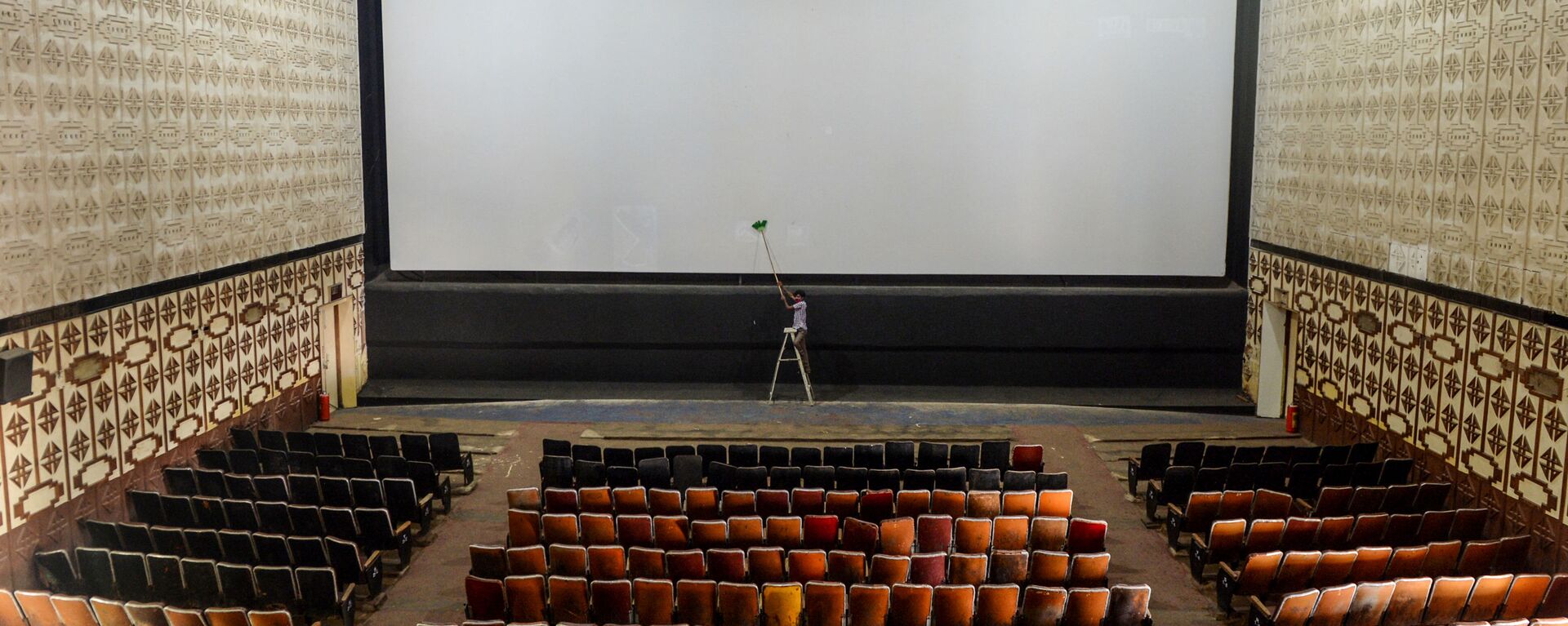 A worker cleans the screen of a cinema hall as part of preparations for a possible reopening after the government eased the lockdown restrictions previously imposed due to the Covid-19 coronavirus, in Chennai on October 8, 2020 - Sputnik International, 1920, 29.08.2021