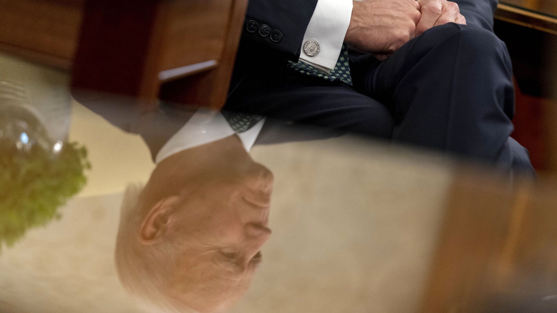 President Joe Biden, seen in reflection, sits next to a bowl of Irish shamrocks, left, as he has a virtual meeting with Ireland's Prime Minister Micheal Martin on St. Patrick's Day, in the Oval Office of the White House, Wednesday, March 17, 2021, in Washington.  - Sputnik International, 1920, 12.02.2022