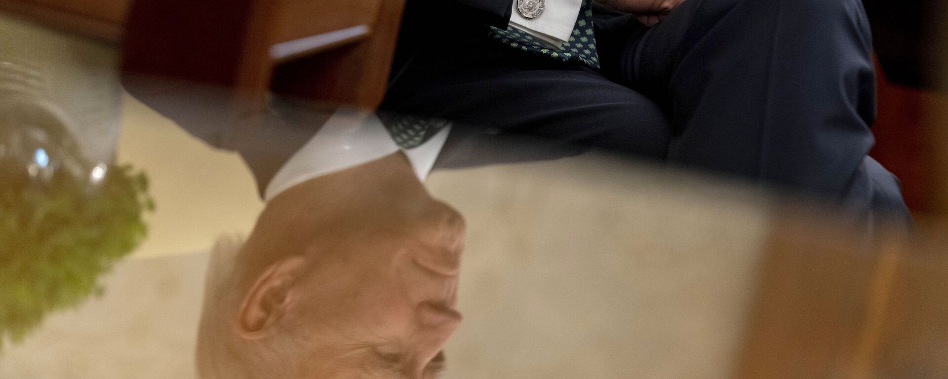President Joe Biden, seen in reflection, sits next to a bowl of Irish shamrocks, left, as he has a virtual meeting with Ireland's Prime Minister Micheal Martin on St. Patrick's Day, in the Oval Office of the White House, Wednesday, March 17, 2021, in Washington.  - Sputnik International, 1920, 15.08.2022