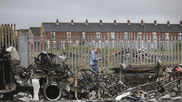 A man walks past a burnt out bus near the loyalist Shankill Road in west Belfast. - Sputnik International