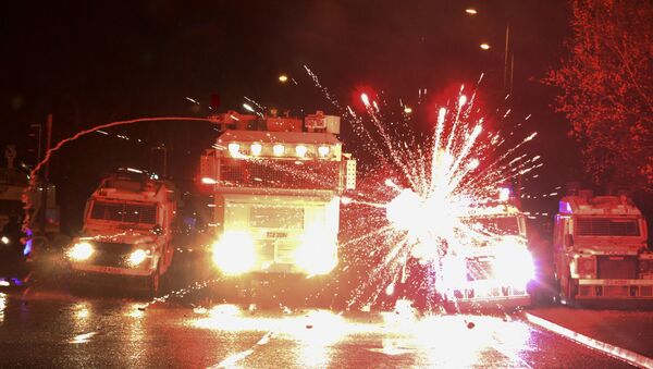 Fireworks explode at police vehicles after being fired at police officers with a water cannon during clashes with nationalist youths in the Springfield Road area of Belfast on April 8, 2021 as disorder continued in the Northern Ireland capital following days of mainly loyalist violence. (Photo by Paul Faith / AFP) - Sputnik International
