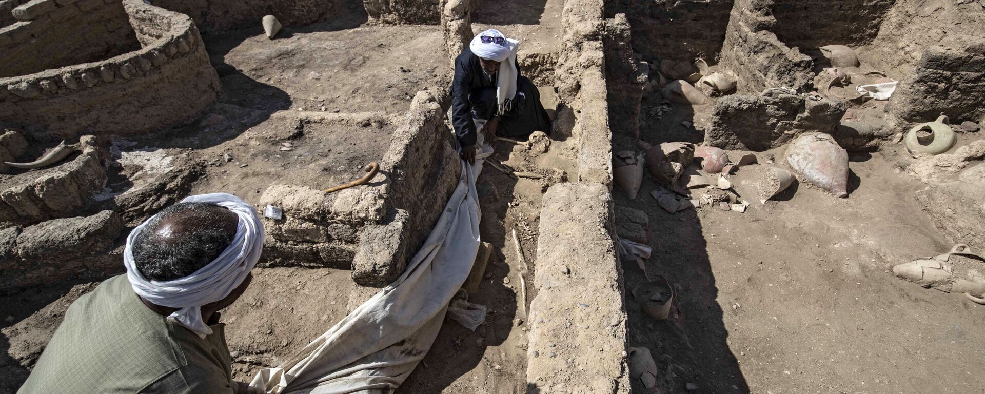 A picture taken on April 10, 2021, shows workers at the archaeological site of a 3000 year old city, dubbed The Rise of Aten, dating to the reign of Amenhotep III, uncovered by the Egyptian mission near Luxor. - Archaeologists have uncovered the remains of an ancient city in the desert outside Luxor that they say is the largest ever found in Egypt and dates back to a golden age of the pharaohs 3,000 years ago. Famed Egyptologist Zahi Hawass announced the discovery of the lost golden city, saying the site was uncovered near Luxor, home of the legendary Valley of the Kings.  - Sputnik International, 1920, 11.04.2021