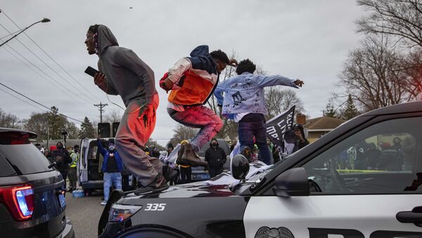 Men jump on the hood of a police car after a family said a man was shot and killed by law enforcement on Sunday, April 11, 2021, in Brooklyn Center, Minn.  - Sputnik International