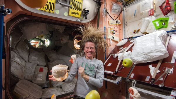 Американский астронавт Карен Найберг с летающими фруктами на МКС  - Sputnik International