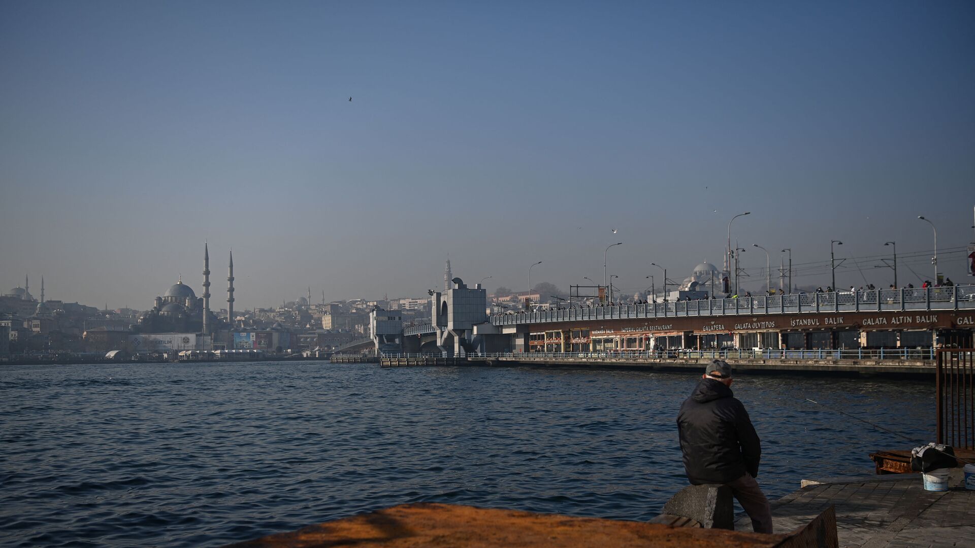A man fishes on shore of Bosphorus straits as Galata bridge is seen in the background, at Karakoy neighbourhood, in Istanbul, on February 23, 2021. - Sputnik International, 1920, 12.02.2022