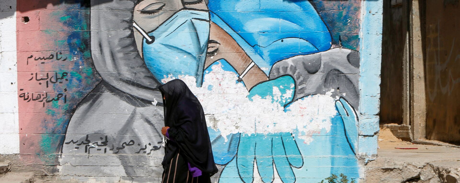 A Palestinian woman walks past a mural, amid the coronavirus disease (COVID-19) outbreak, in the central Gaza Strip March 17, 2021. Picture taken March 17, 2021 - Sputnik International, 1920, 13.04.2021