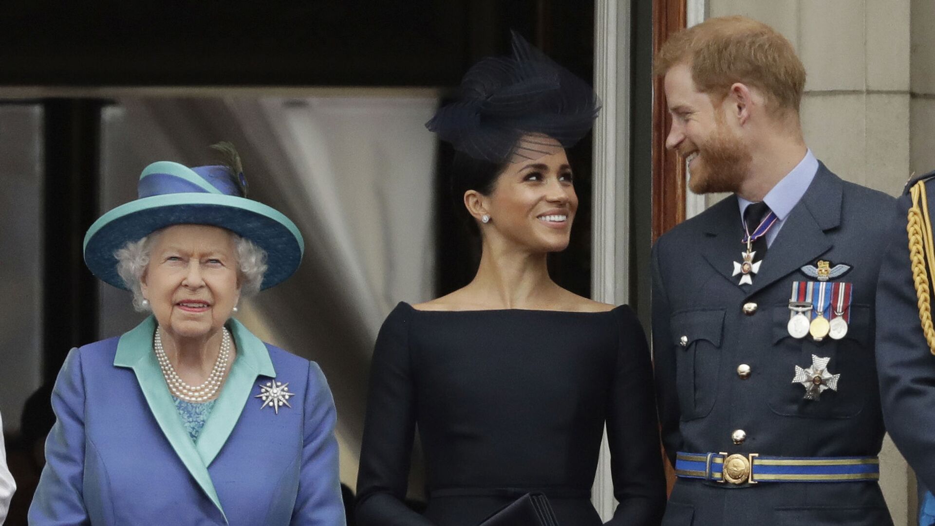 In this 10 July 2018 file photo, Britain's Queen Elizabeth II, Meghan the Duchess of Sussex and Prince Harry watch a flypast of Royal Air Force aircraft pass over Buckingham Palace in London. - Sputnik International, 1920, 09.06.2021