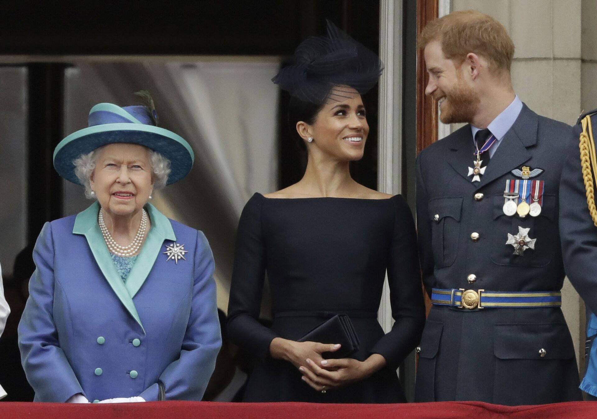 In this Tuesday, July 10, 2018 file photo Britain's Queen Elizabeth II, and Meghan the Duchess of Sussex and Prince Harry watch a flypast of Royal Air Force aircraft pass over Buckingham Palace in London. - Sputnik International, 1920, 07.09.2021
