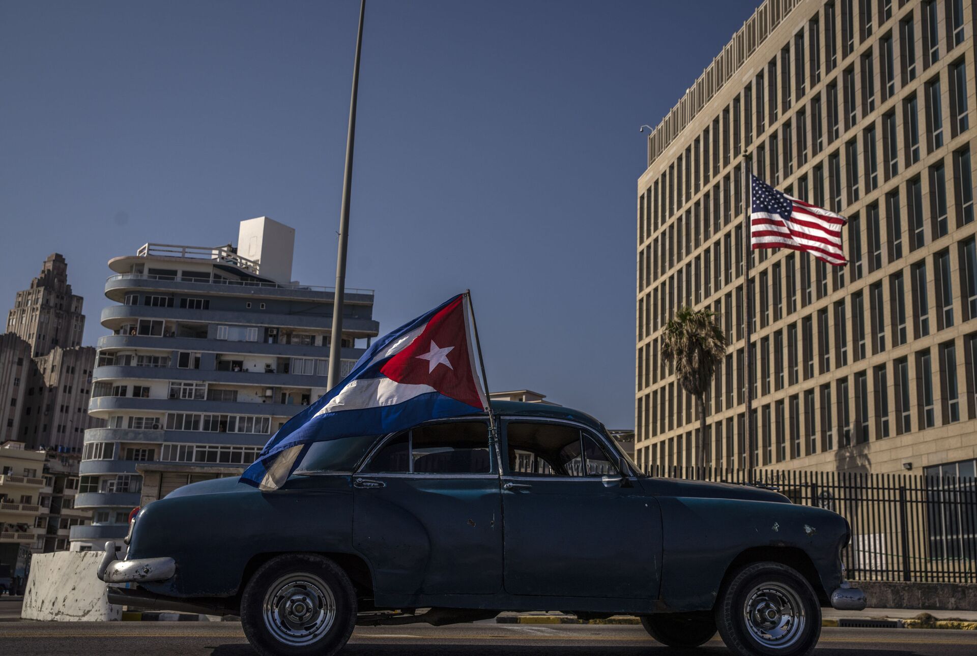 A classic American car flying a Cuban flag drives past the American embassy during a rally calling for the end of the US blockade against the island nation, in Havana, Cuba, Sunday, March 28, 2021. - Sputnik International, 1920, 07.09.2021