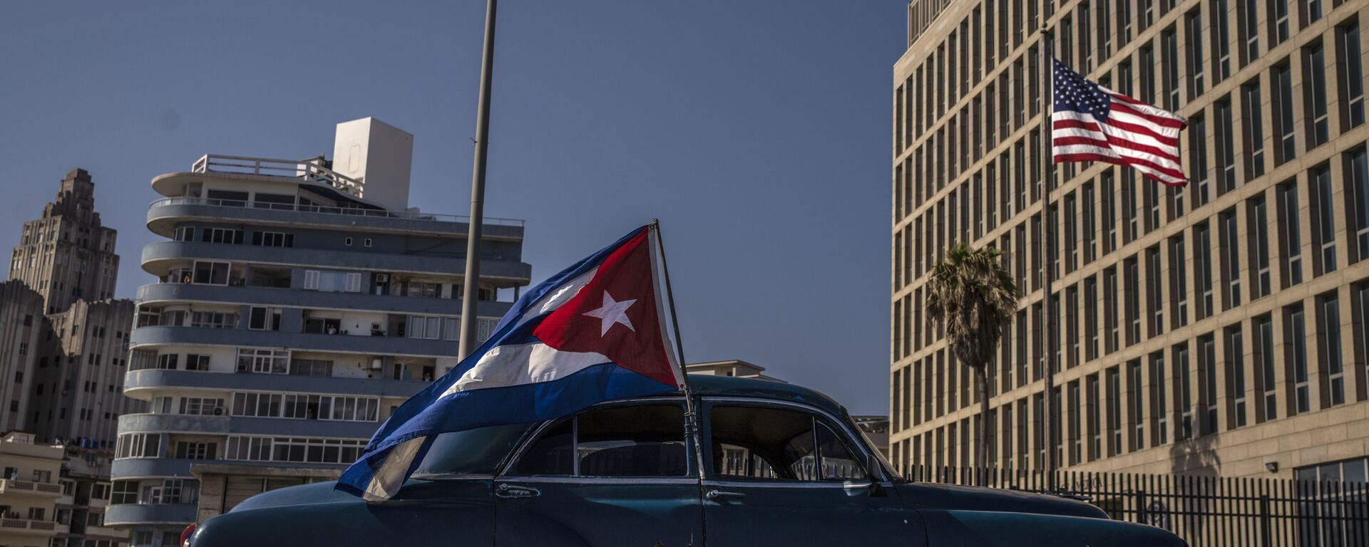 A classic American car flying a Cuban flag drives past the American embassy during a rally calling for the end of the US blockade against the island nation, in Havana, Cuba, Sunday, March 28, 2021. - Sputnik International, 1920, 23.02.2022