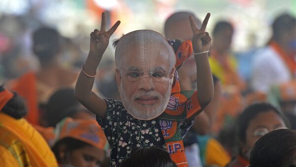 A supporter of Bharatiya Janata Party (BJP) wearing a face cutout of Indian Prime Minister Narendra Modi attends a public rally being addressed by him during the ongoing fourth phase of the West Bengal's state legislative assembly elections, at Kawakhali on the outskirts of Siliguri on April 10, 2021. - Sputnik International
