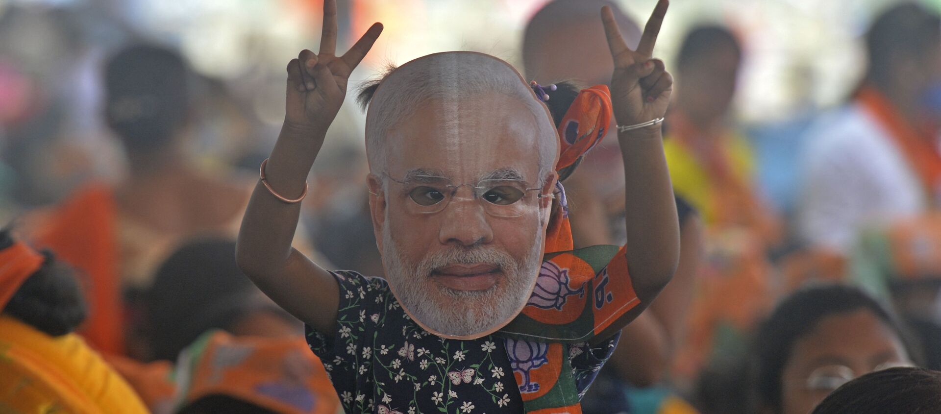 A supporter of Bharatiya Janata Party (BJP) wearing a face cutout of Indian Prime Minister Narendra Modi attends a public rally being addressed by him during the ongoing fourth phase of the West Bengal's state legislative assembly elections, at Kawakhali on the outskirts of Siliguri on April 10, 2021. - Sputnik International, 1920, 07.07.2021