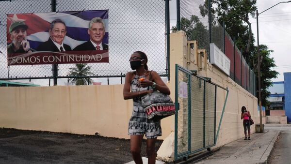 A woman passes by a poster displaying images of late Cuban President Fidel Castro, Cuba's First Secretary of the Communist Party and former President Raul Castro and Cuba's President Miguel Diaz Canel with a sign that reads: We are continuity, in Havana, Cuba, April 12, 2021 - Sputnik International