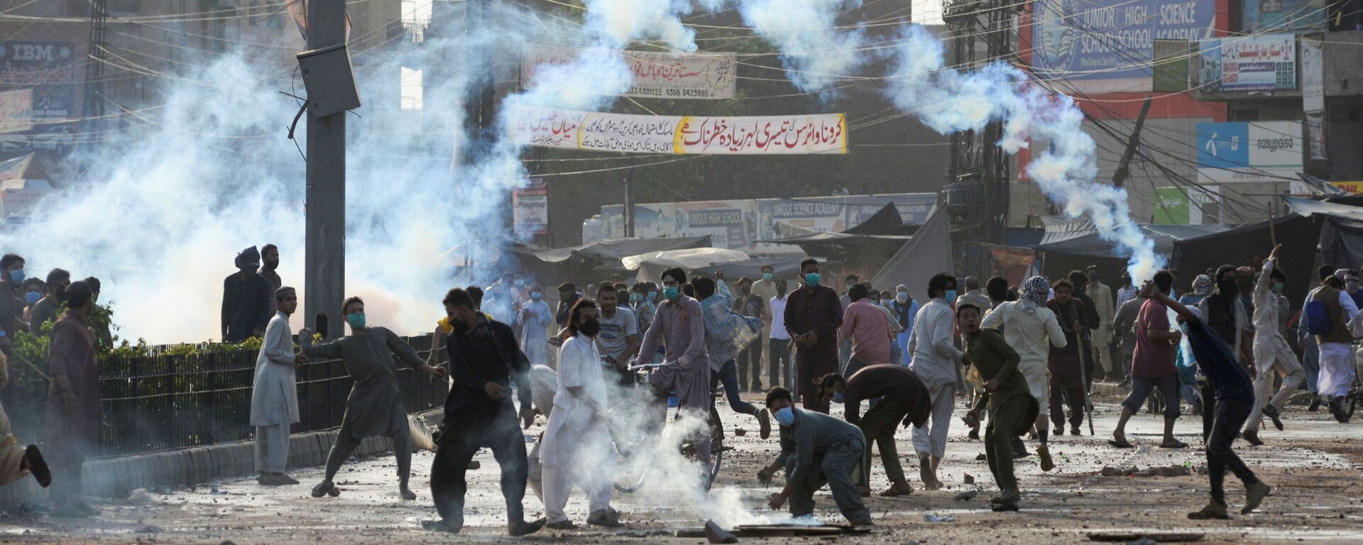 Supporters of the Tehreek-e-Labaik Pakistan (TLP) Islamist political party throwback tear gas canisters fired by police during a protest against the arrest of their leader in Lahore, Pakistan April 13, 2021. - Sputnik International, 1920, 05.11.2021