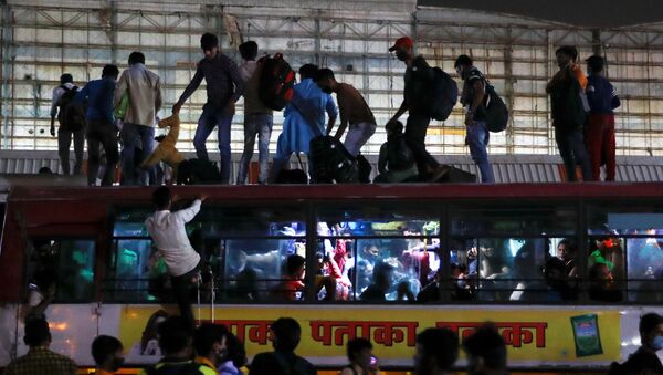 Migrant workers stand on top of an overcrowded bus to return to their villages after Delhi government ordered a six-day lockdown to limit the spread of the coronavirus disease (COVID-19), in Ghaziabad on the outskirts of New Delhi, India, April 19, 2021. - Sputnik International