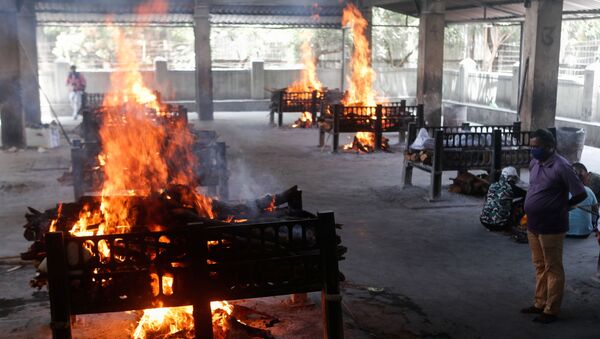 A relative of a coronavirus disease (COVID-19) patient who passed away after a hospital caught fire looks on as funeral pyres burn inside a crematorium in Virar, on the outskirts of Mumbai, India, 23 April 2021 - Sputnik International