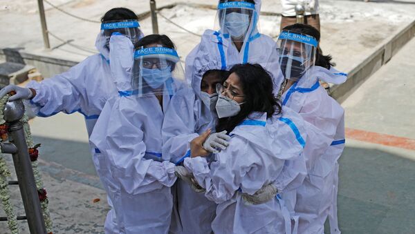 Relatives wearing personal protective equipment (PPE) mourn a man, who died from coronavirus disease (COVID-19), at a crematorium in New Delhi, India April 21, 2021.  - Sputnik International